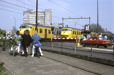 858045 Gezicht op de spoorwegovergang in de Mr. Tripkade te Utrecht, met twee elkaar kruisende electrische treinstellen ...